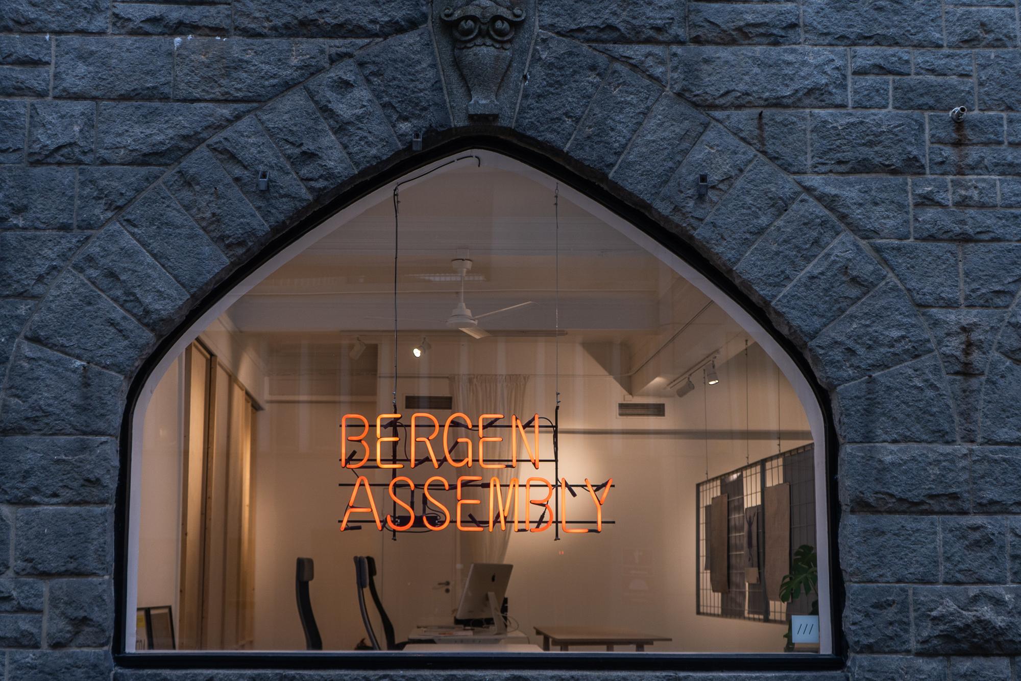 Bergen Assembly sitt neon skilt sett gjennom vinduet i Halfdan Kjerulfs Gate.